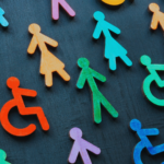 Diverse wooden figures representing gender, disability, and inclusion on a dark background